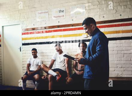 Well guys, lets say I have good news for you. a rugby coach addressing his team players in a locker room during the day. Stock Photo