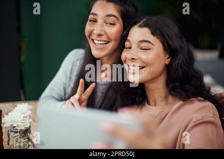 Fun selfies with my favourite person. young sisters taking selfies together at a cafe. Stock Photo