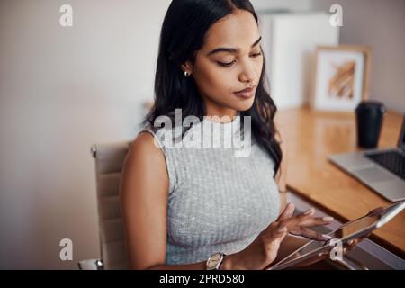 Browsing the web for something new. a young businesswoman using a digital tablet in an office. Stock Photo