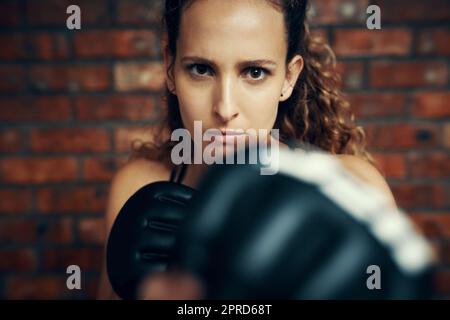 Shes as bad as they get. Cropped portrait of a female kick boxer practicing at the gym. Stock Photo