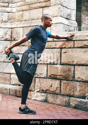 Hes just getting warmed up. Full length shot of a handsome young sportsman stretching and warming before exercising outdoors in the city. Stock Photo