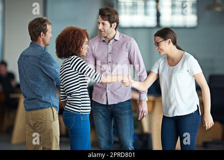 Handshake showing success, support and trust between collaborating business men and women. Smiling, happy and diverse group or team of creative office colleagues making a deal, welcoming and greeting Stock Photo