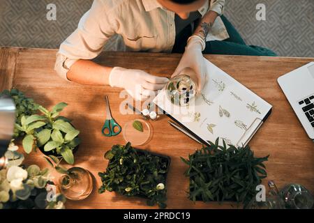 Who wouldnt love working with plants and flowers all day. an unrecognizable botanist adding a liquid nutrient to a water based plant inside a glass jar. Stock Photo