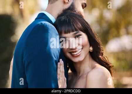 I just married the best man Ive ever met. an affectionate young bride smiling while leaning on her grooms chest on their wedding day. Stock Photo