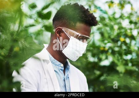 You first have to protect yourself against plant allergies. a young botanist wearing protective eye and face gear while working outdoors in nature. Stock Photo