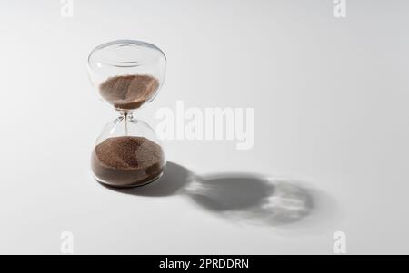 An hourglass placed on a white background. Stock Photo
