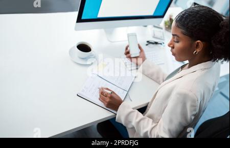 Entrepreneur, secretary and admin assistant holding phone while writing down appointments, schedule and business contacts at her desk. Professional woman doing online research and making notes Stock Photo