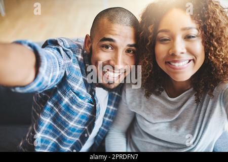 Happy couple taking selfies as home owners, bonding or enjoying new real estate purchase. Portrait of smiling or proud man and woman celebrating and capturing memory picture as home investors Stock Photo