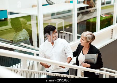Moving up and straight towards success. two businesspeople walking up a staircase together in an office. Stock Photo