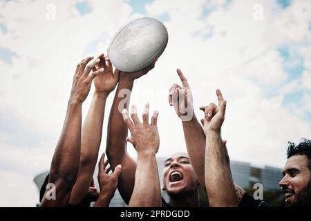 They dont call us the champions for nothing. a team of rugby players celebrating while standing on the field during the day. Stock Photo