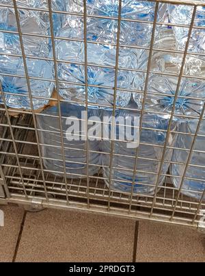Storage and transportation of large plastic bottles for clean drinking water in a container with a metal grate, close-up Stock Photo