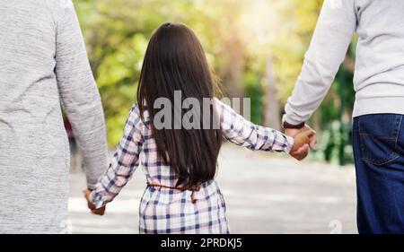 Handing down our love form one generation to the next. Rearview shot of an unrecorgnizable little girl holding hands with her grandparents while walking through the park. Stock Photo