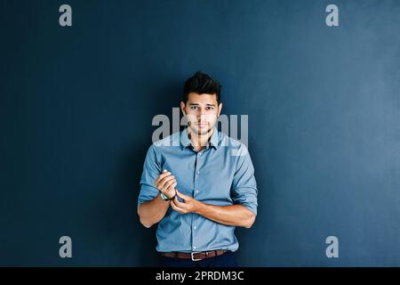 Theres a long way to go but Im ready. Studio portrait of a handsome young businessman adjusting his wristwatch while standing against a grey background. Stock Photo