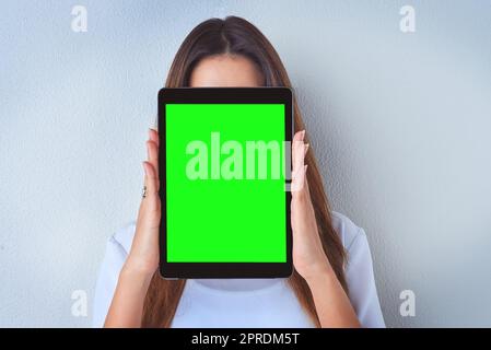 Shes hiding behind her posts online. an unrecognizable woman holding a digital tablet against a blue background. Stock Photo
