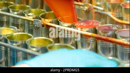 Canned fish factory. Food industry. Machine filling red tomato sauce into sardine can at food factory. Food processing production line. Food manufacturing industry. Cans of sardines on conveyor belt. Stock Photo