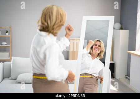 Smiling Slim Woman Looking At Her Reflection Stock Photo