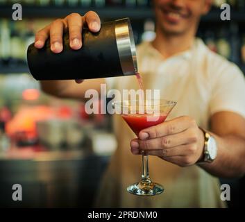 Keep pouring those drinks. an unrecognizable barman pouring a drink in a fancy glass inside of a restaurant during the day. Stock Photo