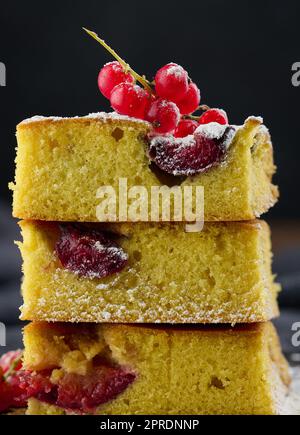 A stack of square slices of baked plum biscuit cake, sprinkled with powdered sugar on top Stock Photo