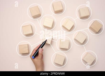 Wooden cubes are connected by lines on a beige background. Stock Photo