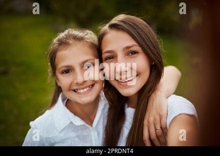 Were as close as can be. Cropped portrait of two young sisters taking selfies in the park. Stock Photo