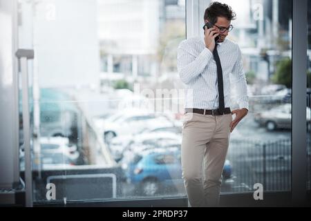 Stay connected, stay successful. a young businessman talking on a cellphone in an office. Stock Photo