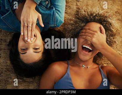 Shes super shy. High angle shot of two attractive young girlfriends lying down together outdoors. Stock Photo