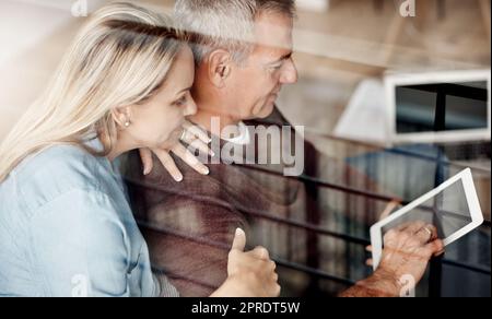 Logged in and loved up. a mature couple using a digital tablet while relaxing together on the sofa at home. Stock Photo