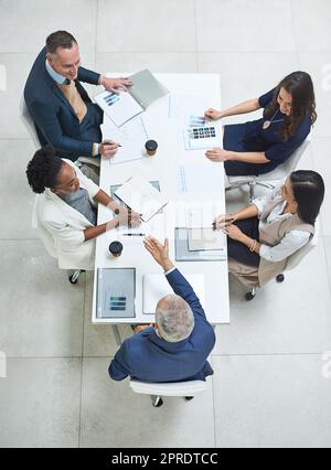 Teamwork, talking and meeting group of corporate colleagues planning, brainstorming or discussing ideas. Above desk of leader asking diverse team questions and collaborating with reports or documents Stock Photo