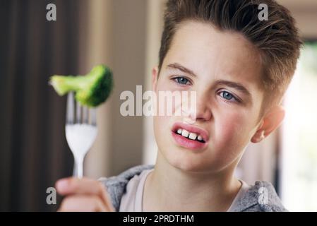 Who invented vegetables anyway. a young boy refusing to eat his broccoli at home. Stock Photo