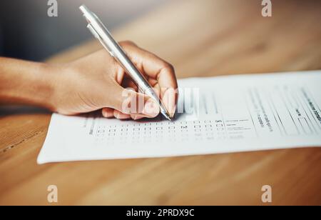 Her opinion matters. Closeup of a female hand filing in paperwork for a formal application or survey. A woman writing on a form applying for a financial loan, completing a list or questionnaire. Stock Photo