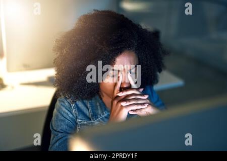 Shes on the late shift... again. a young businesswoman looking stressed out while working late in an office. Stock Photo
