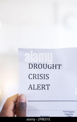 Be aware of the drought. Closeup of an unrecognizable person holding a paper with a notification on it saying drought crisis alert. Stock Photo