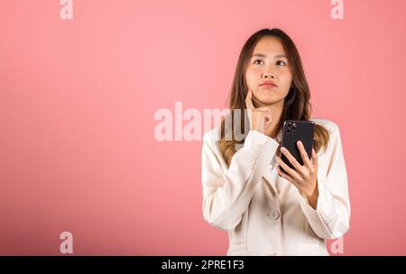 young woman excited smiling holding mobile phone and think idea finger touch face Stock Photo