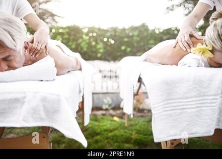 We should make this a weekend thing. a middle aged couple having a relaxing massage together at a spa during the day. Stock Photo