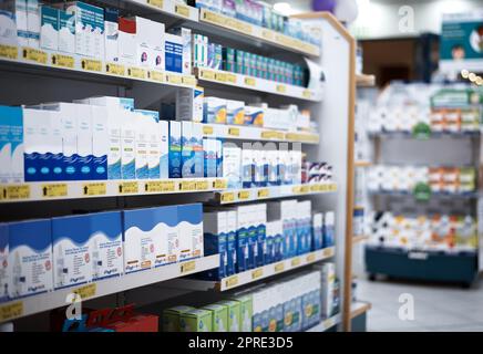Every aisle is stocked with the health essentials you need. shelves stocked with various medicinal products in a pharmacy. Stock Photo