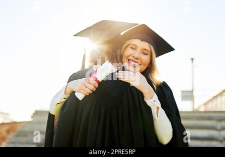 Im so happy to have made this journey with you. two students hugging each other on graduation day. Stock Photo