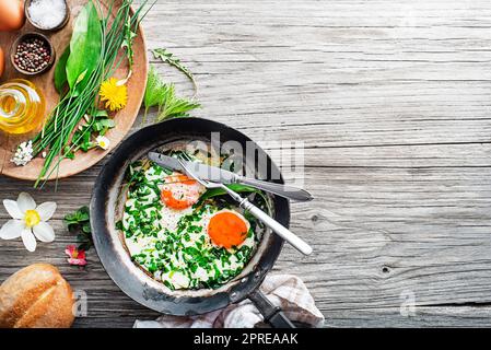 Fried eggs with fresh spring plants and herbs. Healthy spring food concept. Stock Photo