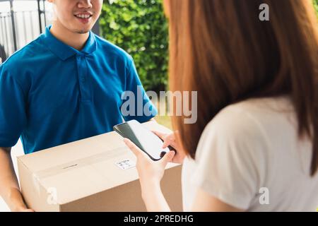 Asian customer young woman using mobile smartphone with QR code payment to receive parcel post box from delivery man, Hands of female scanning at door Stock Photo