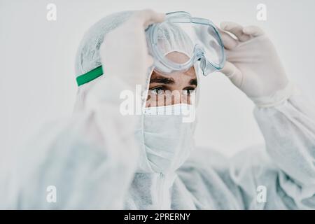 Covid, pandemic and healthcare worker wearing protective ppe to prevent virus spread at a quarantine site or hospital. Closeup of a doctor or scientist wearing a hazmat suit and goggles for safety Stock Photo