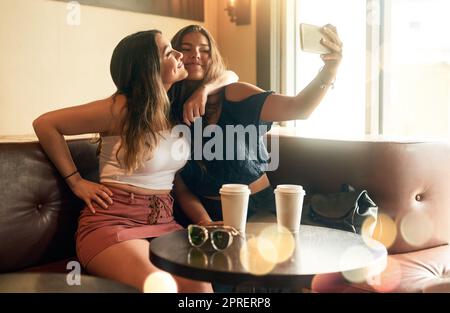 Bring it in. two attractive young women taking selfies in their local cafe. Stock Photo