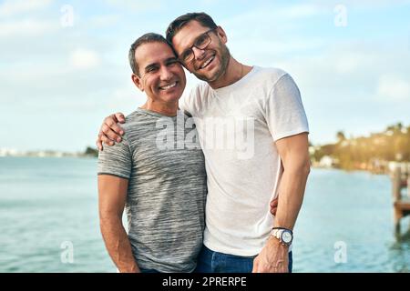 They love going to the beach together. Portrait of an affectionate mature couple spending the day by the beach. Stock Photo