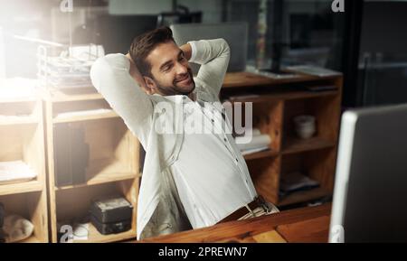 Kicking back after a long but successful day. a handsome young businessman taking a break while working late in an office. Stock Photo