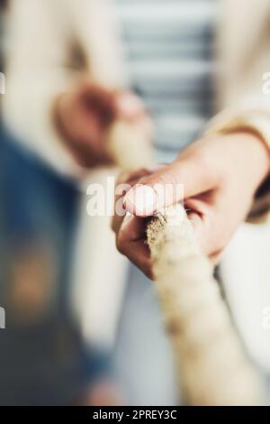 I have to work hard to get to the top. Closeup of an unrecognizable businesswoman pulling on a rope inside of a office during the day. Stock Photo