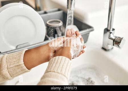 Hygiene, cleaning and washing hands with soap and water in the kitchen sink at home. Closeup of a female lathering and rinsing to disinfect, protect and prevent the spread of virus and germs Stock Photo