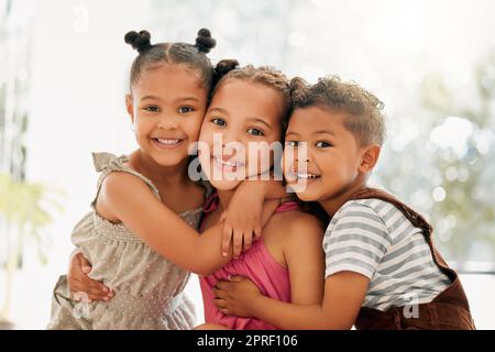 Siblings, boy and girl children hugging and bonding together as a cute happy family indoors during summer. Portrait of young, brother and sister kids smiling, embracing and enjoying their childhood Stock Photo
