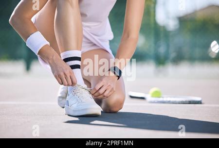 Female tennis player foot and hands tying shoelaces before game match on outdoor sports court. Active, sporty woman preparing for training for fun, summer exercise and healthy, wellness lifestyle. Stock Photo