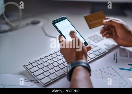 Paying accounts on the go. High angle shot of an unrecognizable man doing online banking using his cellphone. Stock Photo
