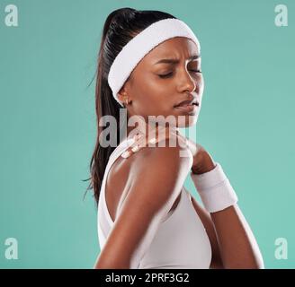 Sports injury, shoulder pain and tennis player suffering with sore muscles after a game while standing against a studio background. Painful, hurt and discomfort after training or playing in a match Stock Photo