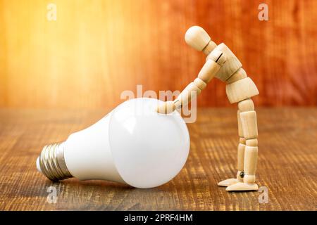 Wooden dummy with LED light bulb on wooden background Stock Photo