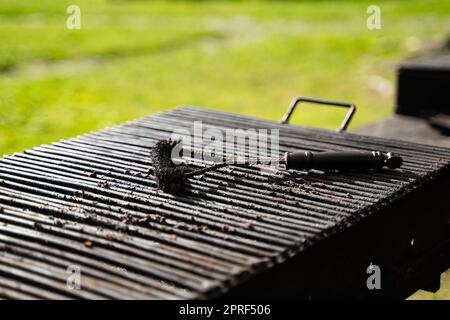 outdoor barbeque grill with black brush tool for cleaning on top Stock Photo